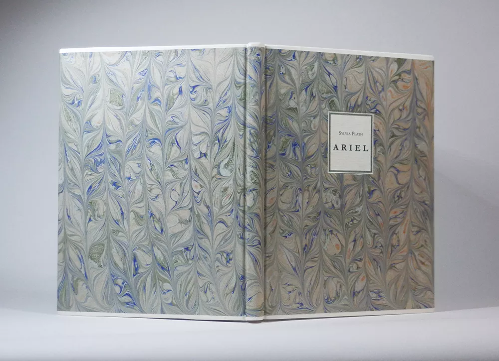 Sylvia Plath „Ariel“ (Faber & Faber, 1968). Specialiai maketuotas leidinys.  Millimeter binding, arba Danish Rubow, stiliaus įrišimas. Baltos, alūnu išdirbtos ožkos odos juostelės, rankų darbo marmurinis popierius, popierinė lipdė; 16,5 x 22 x 1,3 cm.