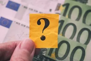 Person holds yellow paper note with question mark in his hand ag