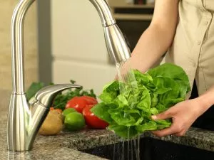 woman's hands washing lettuce in kitchen sink